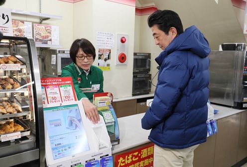 Photograph of the Prime Minister charging the prepaid electronic money card issued to him 