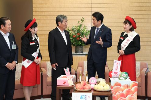 Photograph of the Prime Minister being presented with the peaches