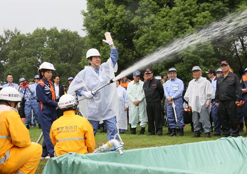 Photograph of the Prime Minister participating in the firefighting drill using a standpipe fire hose