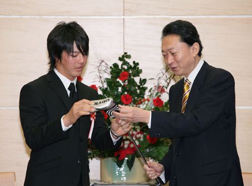 Photograph of the Prime Minister looking at a putter presented by Mr. Ishikawa