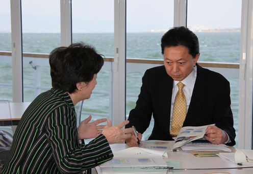 Photograph of the Prime Minister receiving an explanation from the Governor of Shiga Prefecture on board an environment-friendly cruise ship