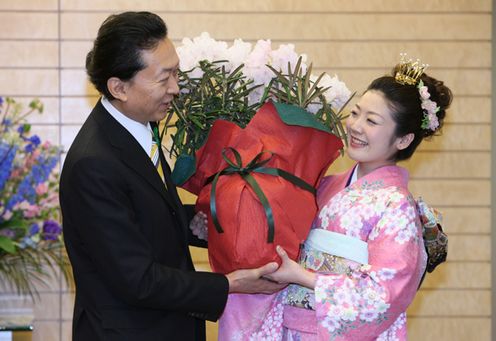 Photograph of the Prime Minister being presented with a rhododendron from the Japan Cherry Blossom Queen