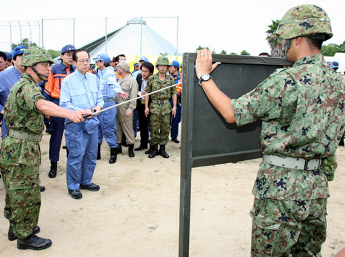 Photograph of the Prime Minister receiving an explanation on the use of tents for temporary housing