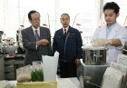 Photograph of the Prime Minister observing grinding up of food samples for testing