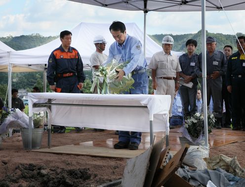 Photograph of the Prime Minister offering flowers at the site of the landslide