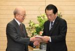Photograph of the Prime Minister receiving the collection of research achievements from Emeritus Professor of Hokkaido University Akira Suzuki