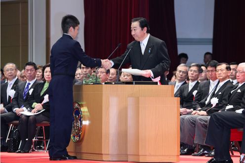 Photograph of the Prime Minister receiving a written oath from an officer candidate and giving a handshake of encouragement