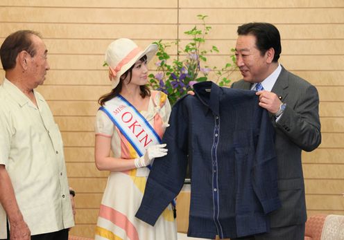 Photograph of the Prime Minister receiving an explanation from Miss Okinawa on the patterns of the <i>kariyushi</i> shirts presented