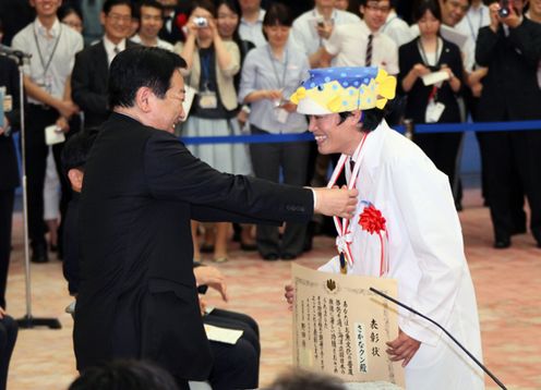Photograph of the Prime Minister presenting a medal to Sakana-kun at the ceremony to commend contributors to promote the country as a 