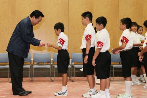 Photograph of the Prime Minister exchanging business cards with junior reporters